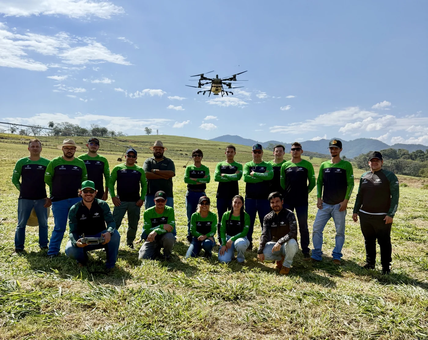 Turma da Drones Academy reunida no campo com um drone agrícola em voo